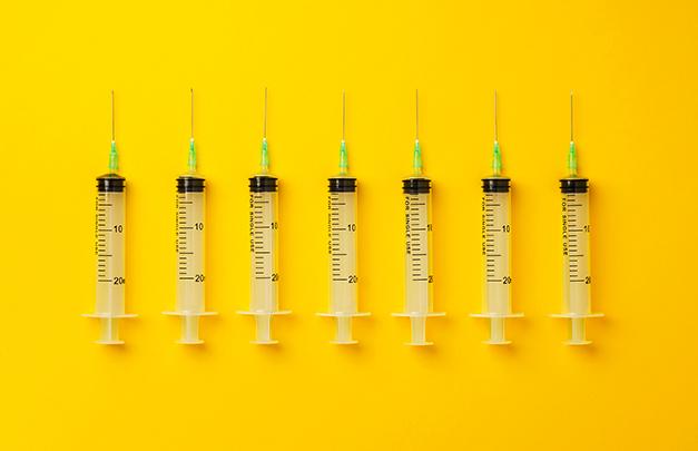 line of syringes against a yellow background